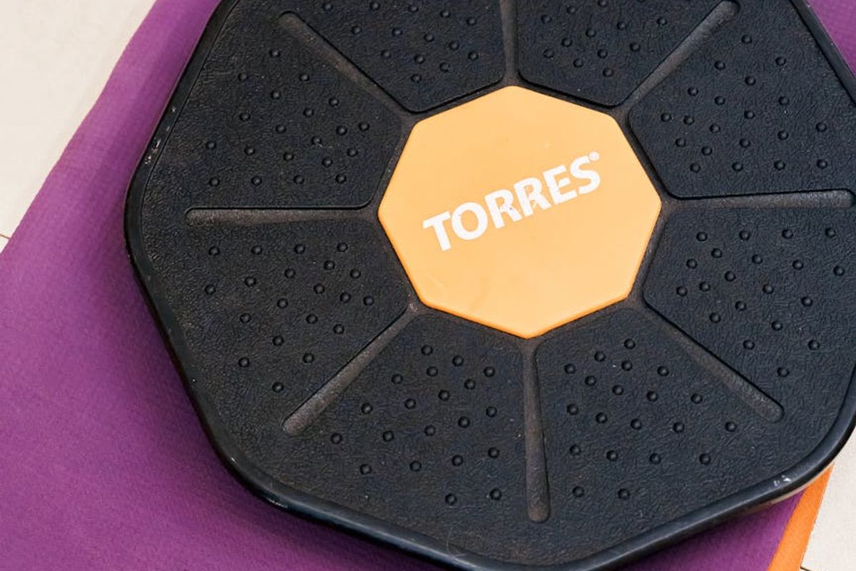 Woman performing core stability exercises on a black mat.